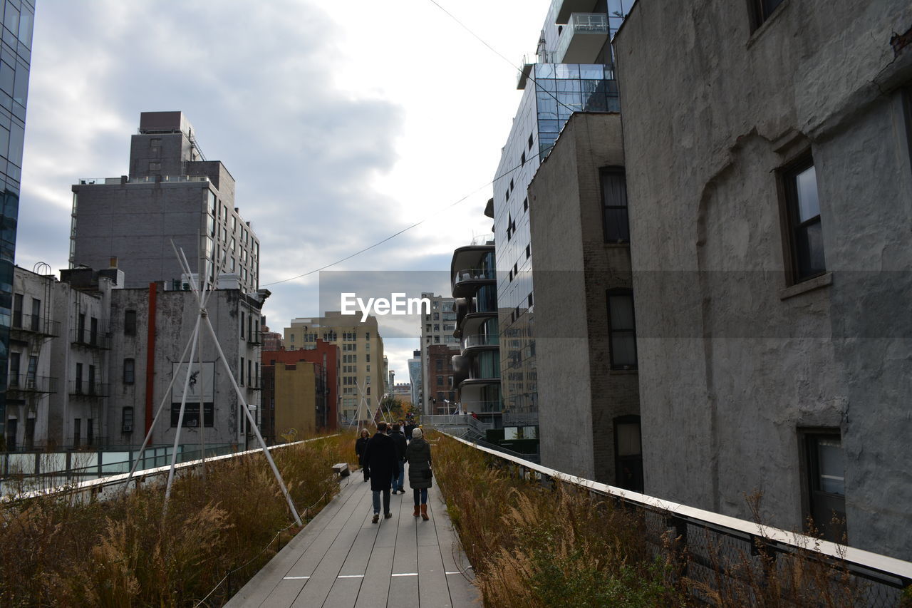 architecture, built structure, building exterior, urban area, city, road, sky, building, walking, street, cityscape, adult, nature, lifestyles, men, city life, cloud, transport, rear view, lane, transportation, full length, downtown, women, residential district, neighbourhood, day, waterway, outdoors, footpath, two people, the way forward, town, infrastructure, leisure activity