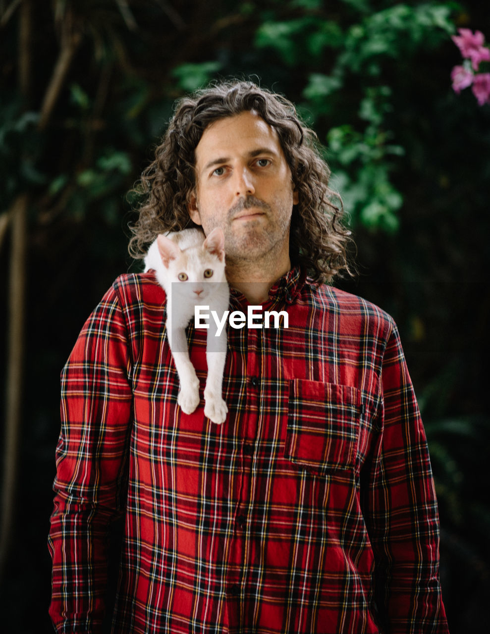 Portrait of man with cat on shoulder outdoors