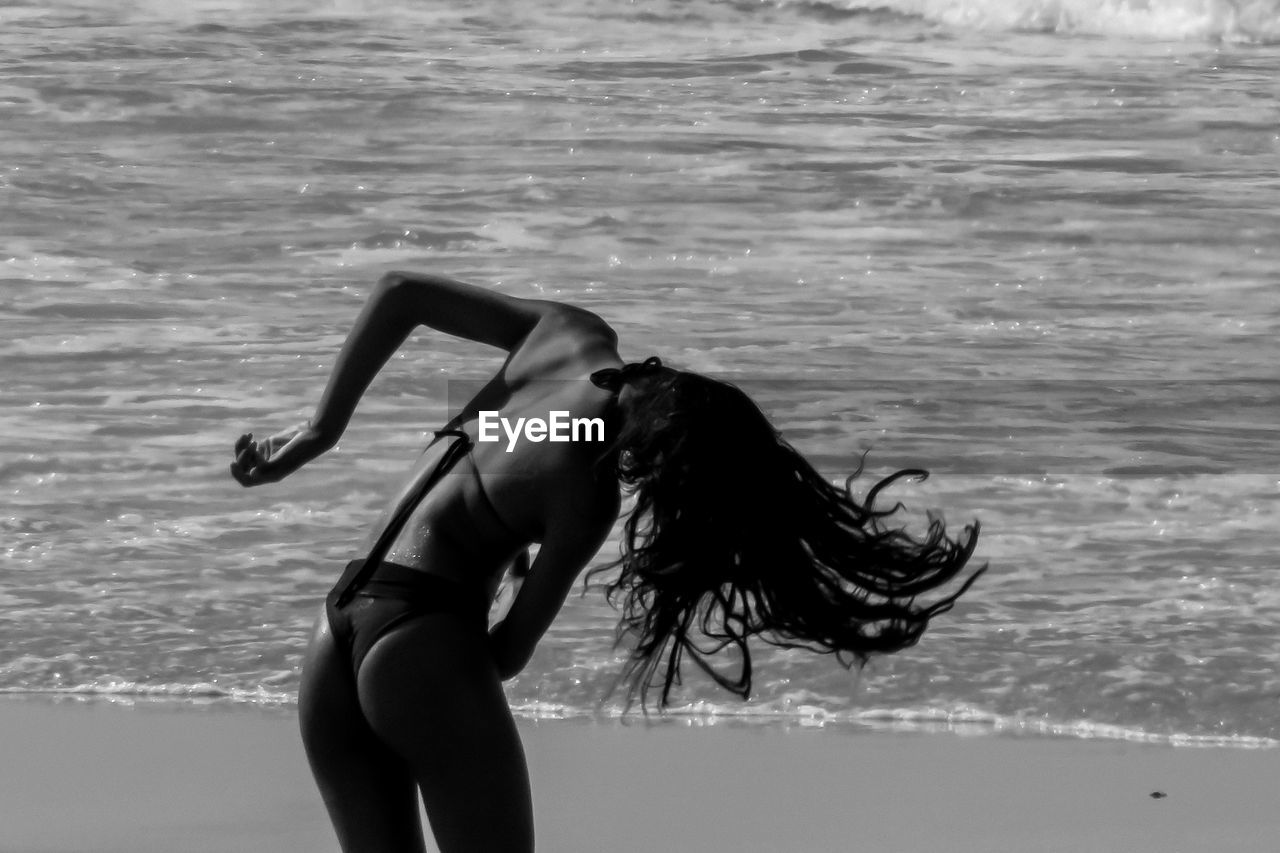 Rear view of woman tossing hair at beach