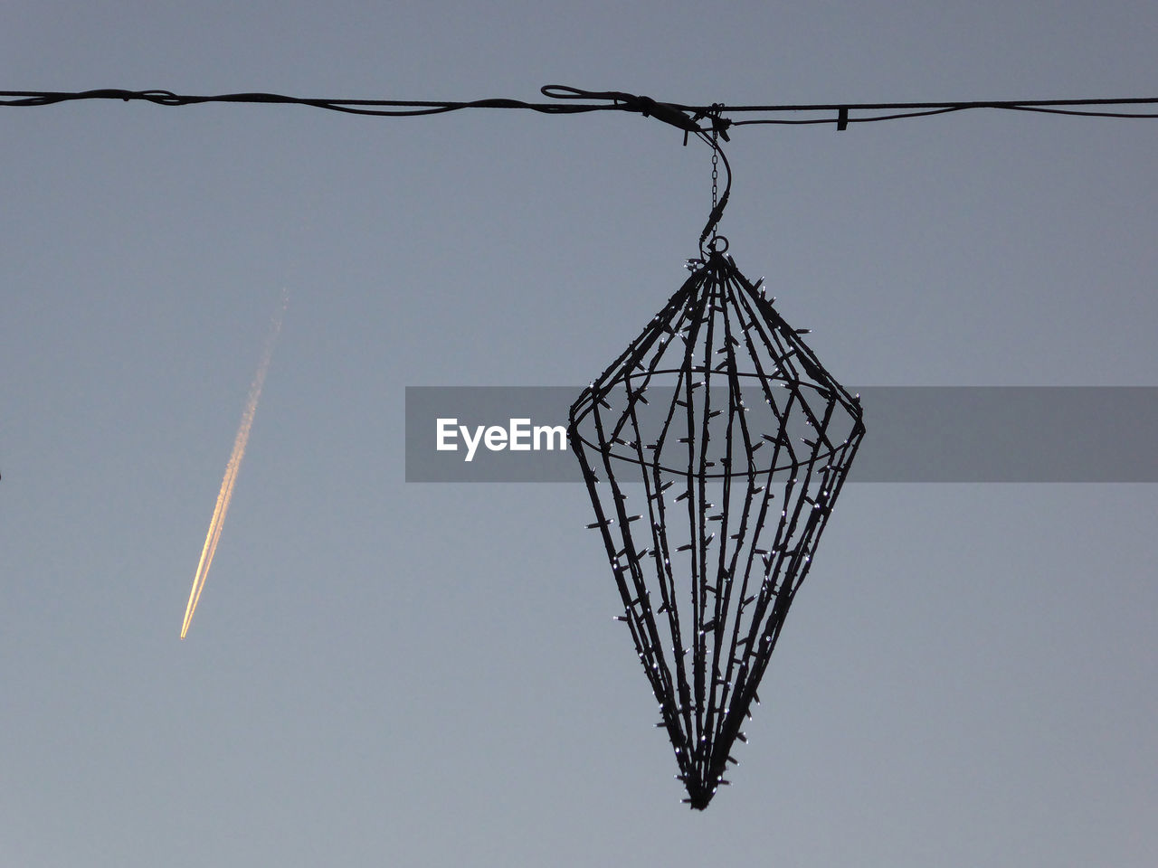 Low angle view of christmas decoration and plane trail against sky