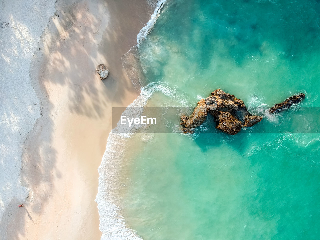 Drone view of a rock in the water at otama beach near matarangi, coromandel peninsula in new zealand