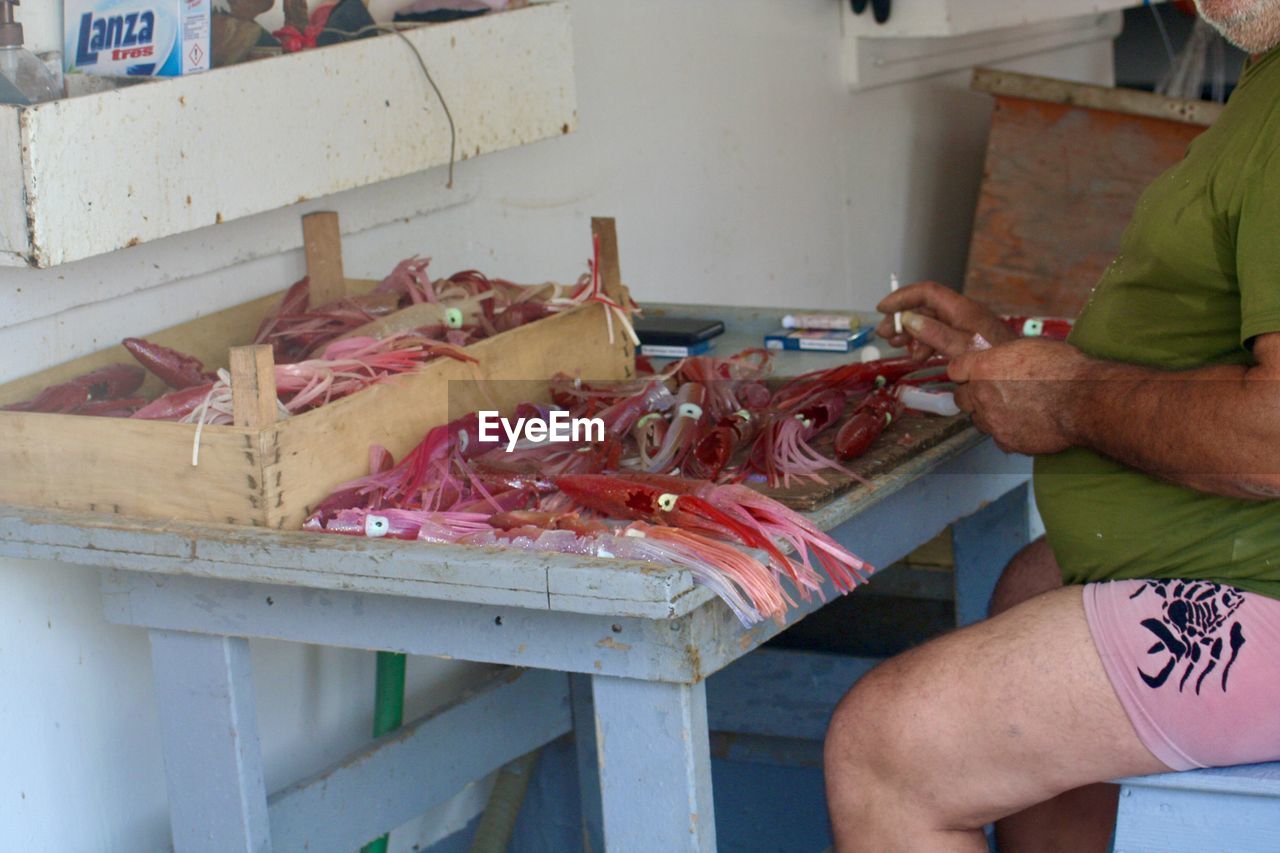 MIDSECTION OF MAN PREPARING FISH IN KITCHEN