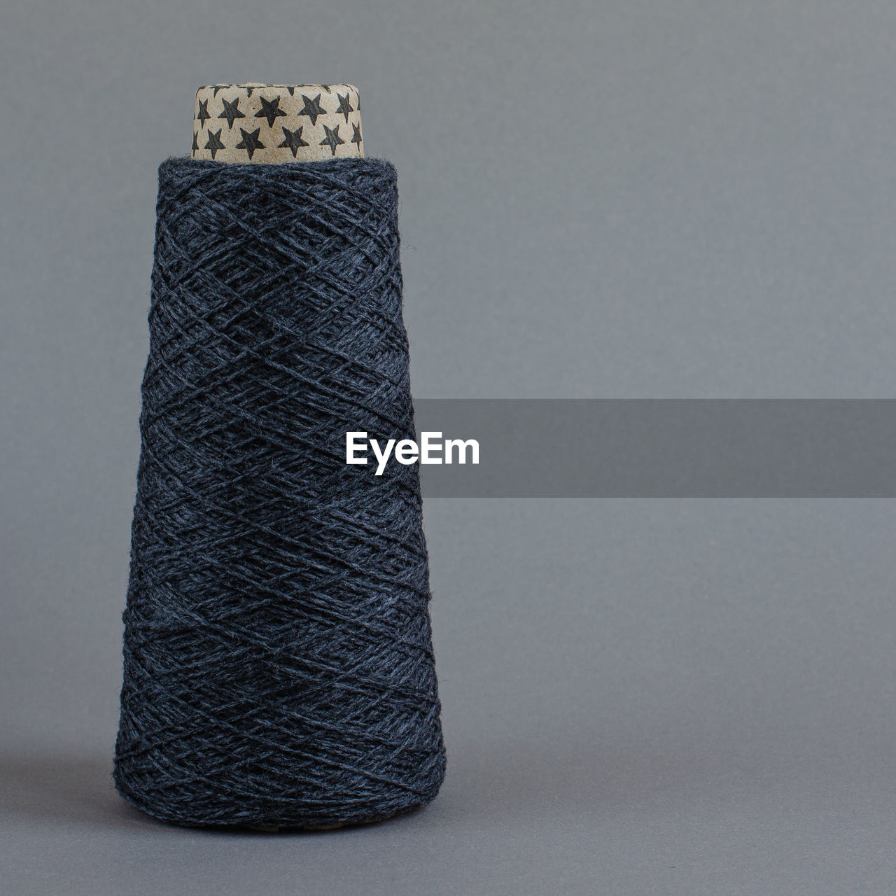 Cone of gray wool yarn on light gray background. copy space