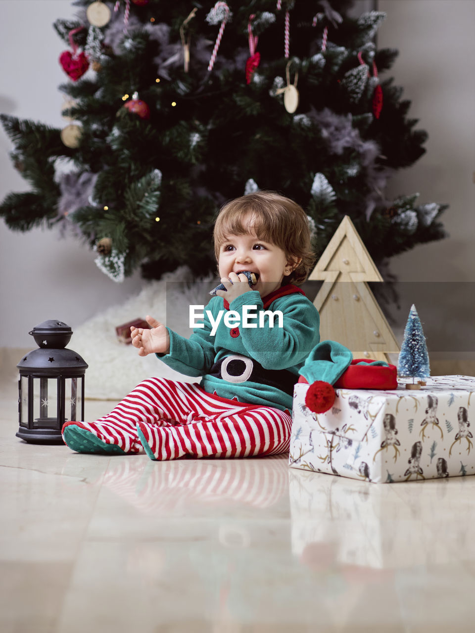 A little 12-month-old christmas elf with a christmas tree and gifts