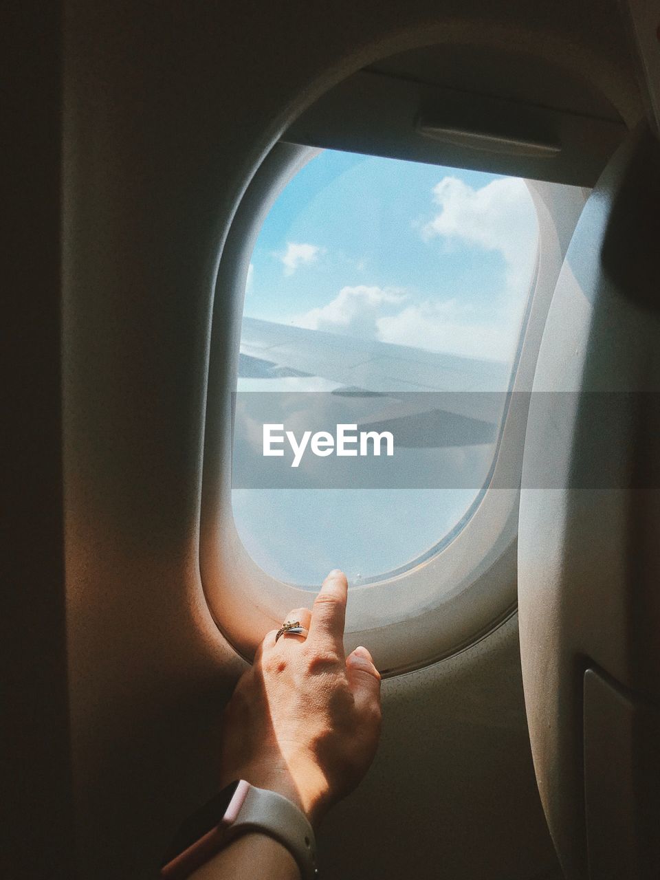 Cropped hand of woman touching window in airplane