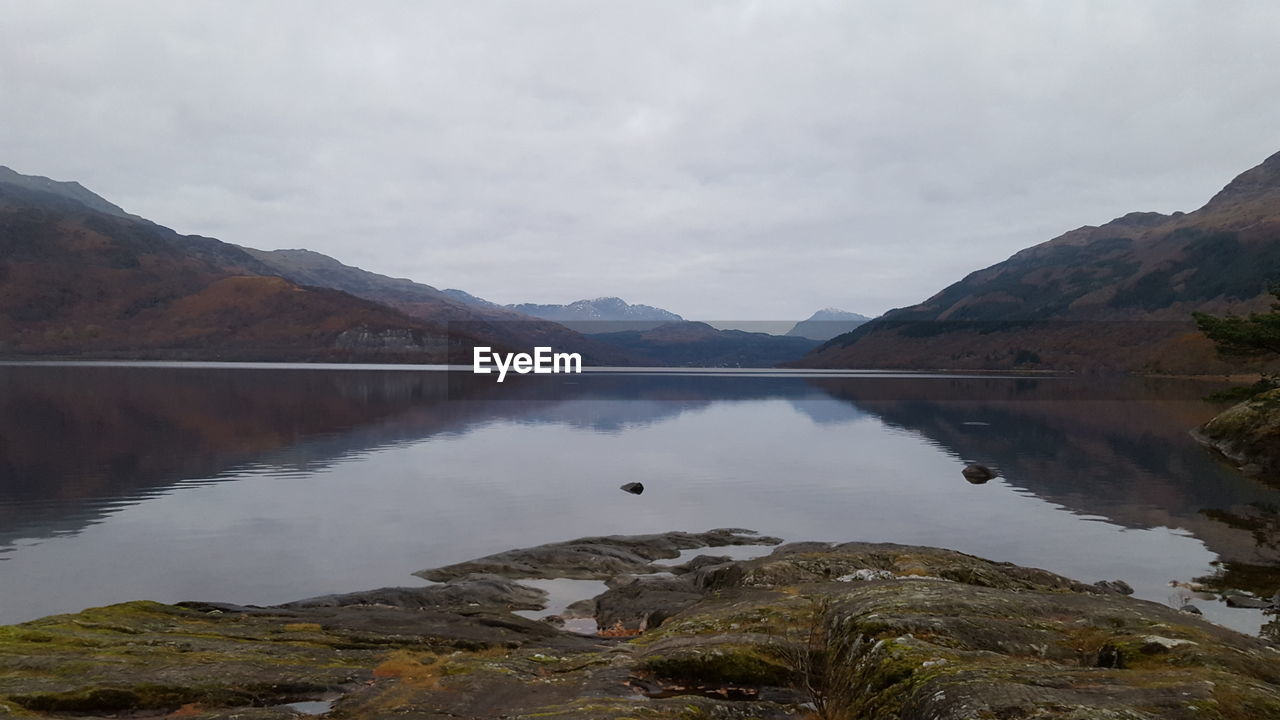 SCENIC VIEW OF LAKE BY MOUNTAIN AGAINST SKY