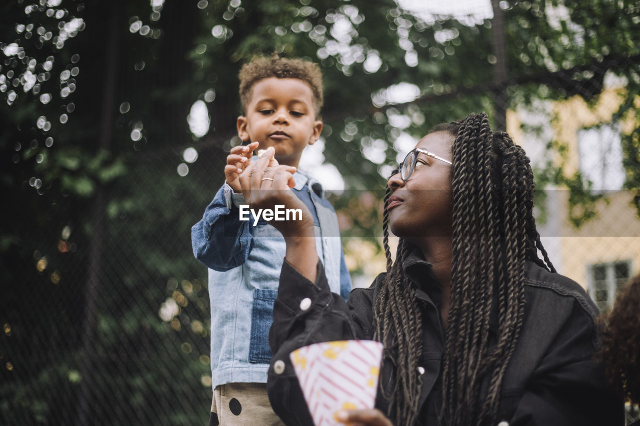 Low angle view of mother giving popcorn to son at amusement park