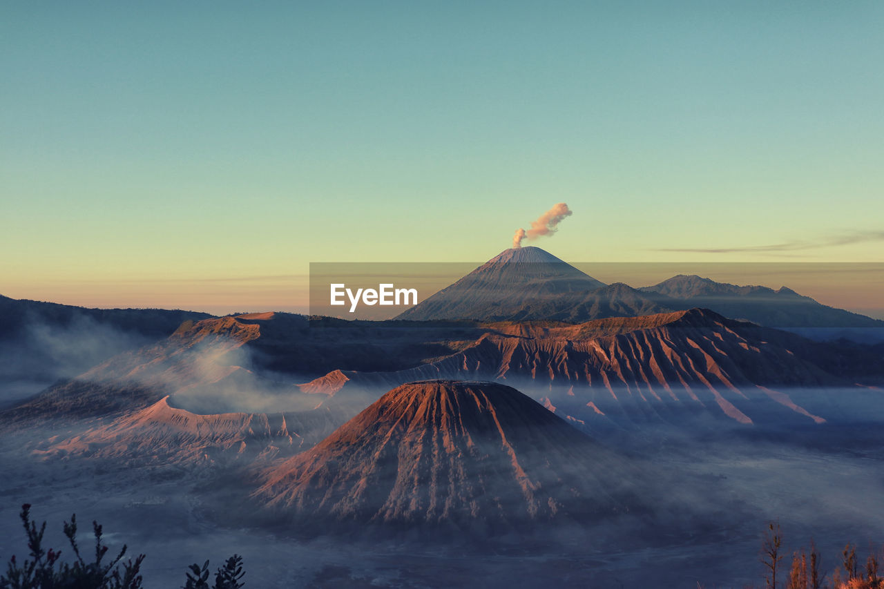 Volcanic mountains against sky during sunset