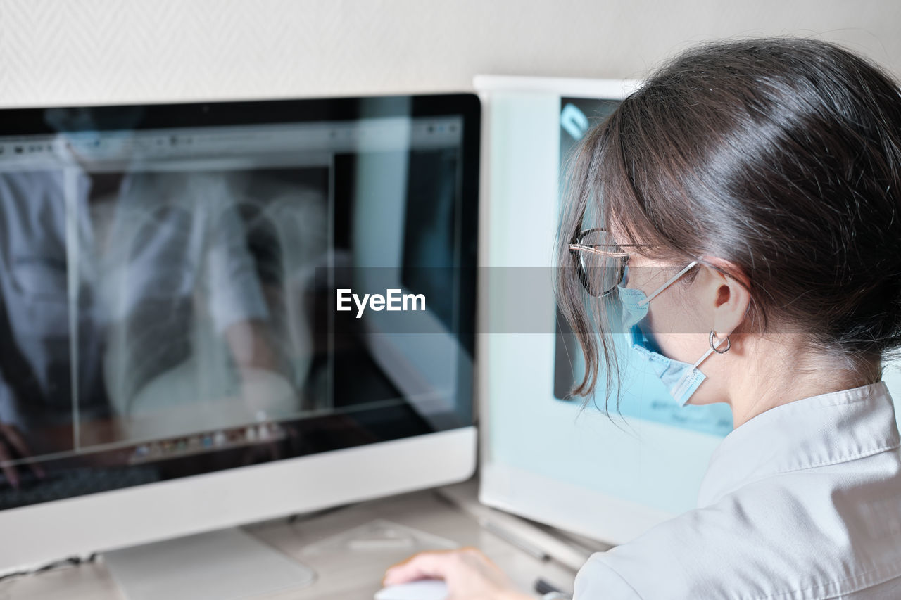 Young asian woman radiologist doctor analysis pulmonary x-ray and make a medical description