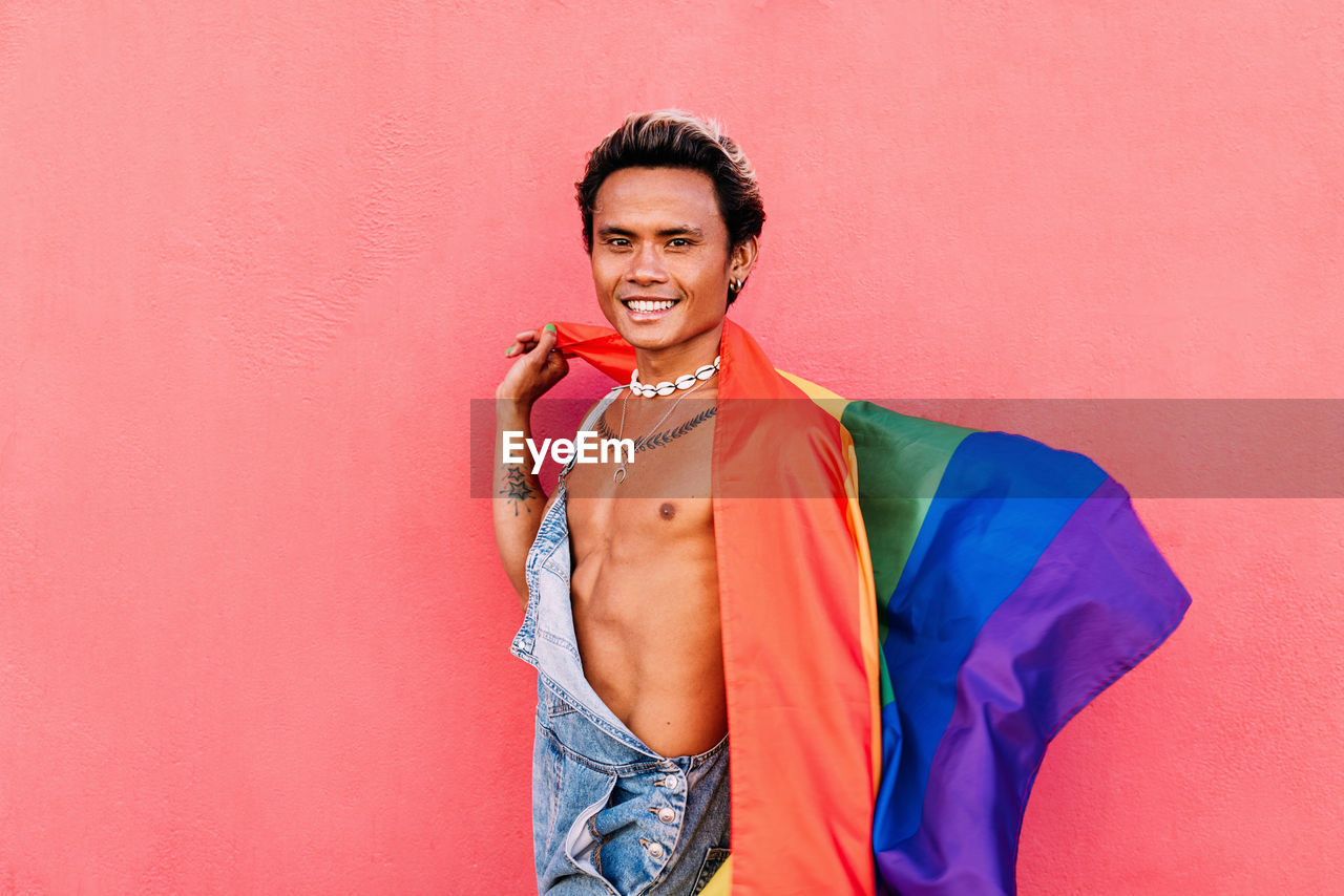Portrait of young man with rainbow flag