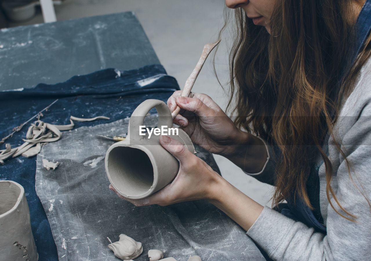 Midsection of woman making clay cup