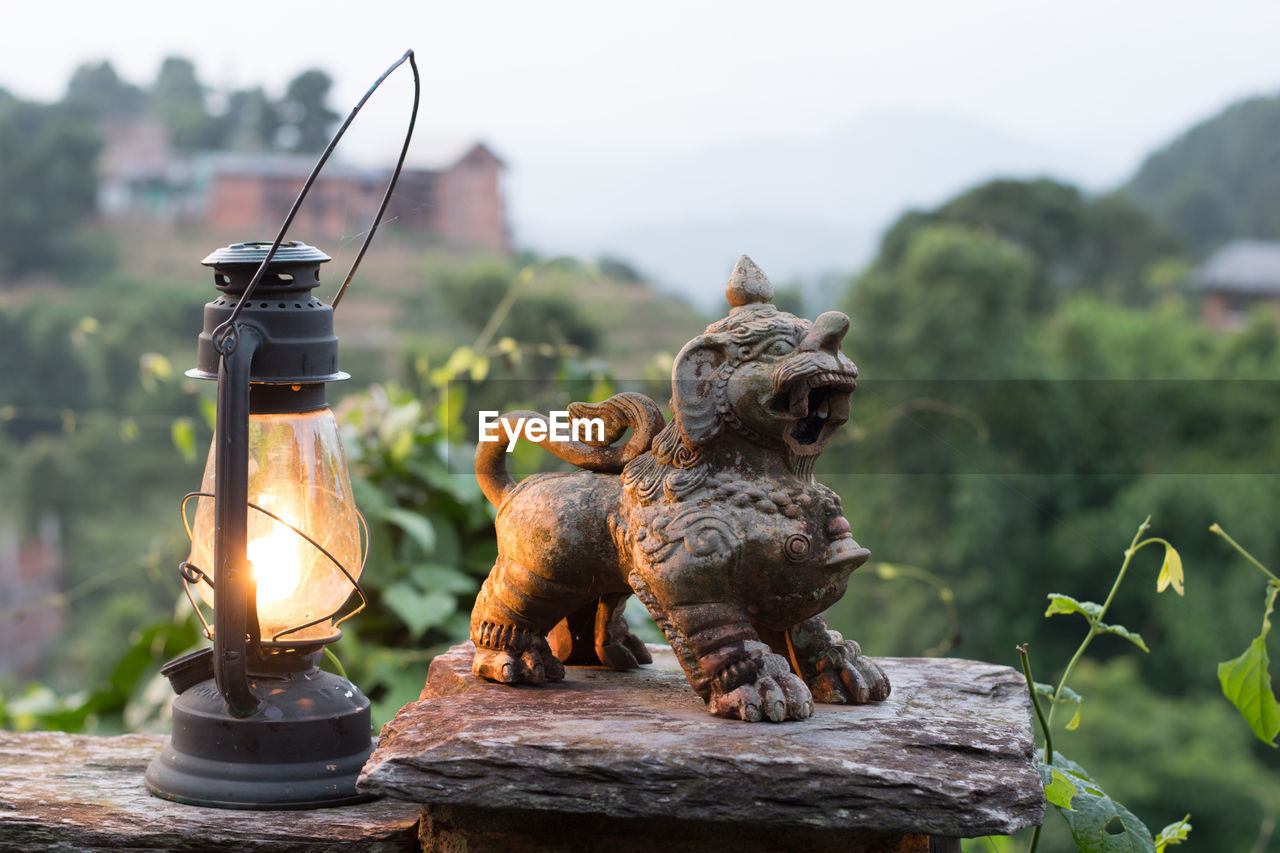 CLOSE-UP OF LION STATUE BY TOY ON WOOD