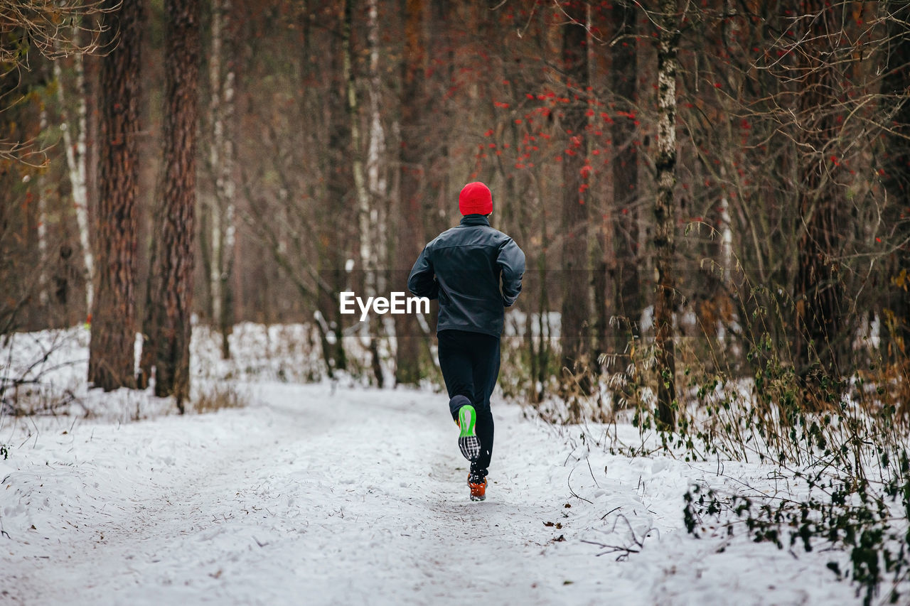 Male runner running trail in winter snowy forest
