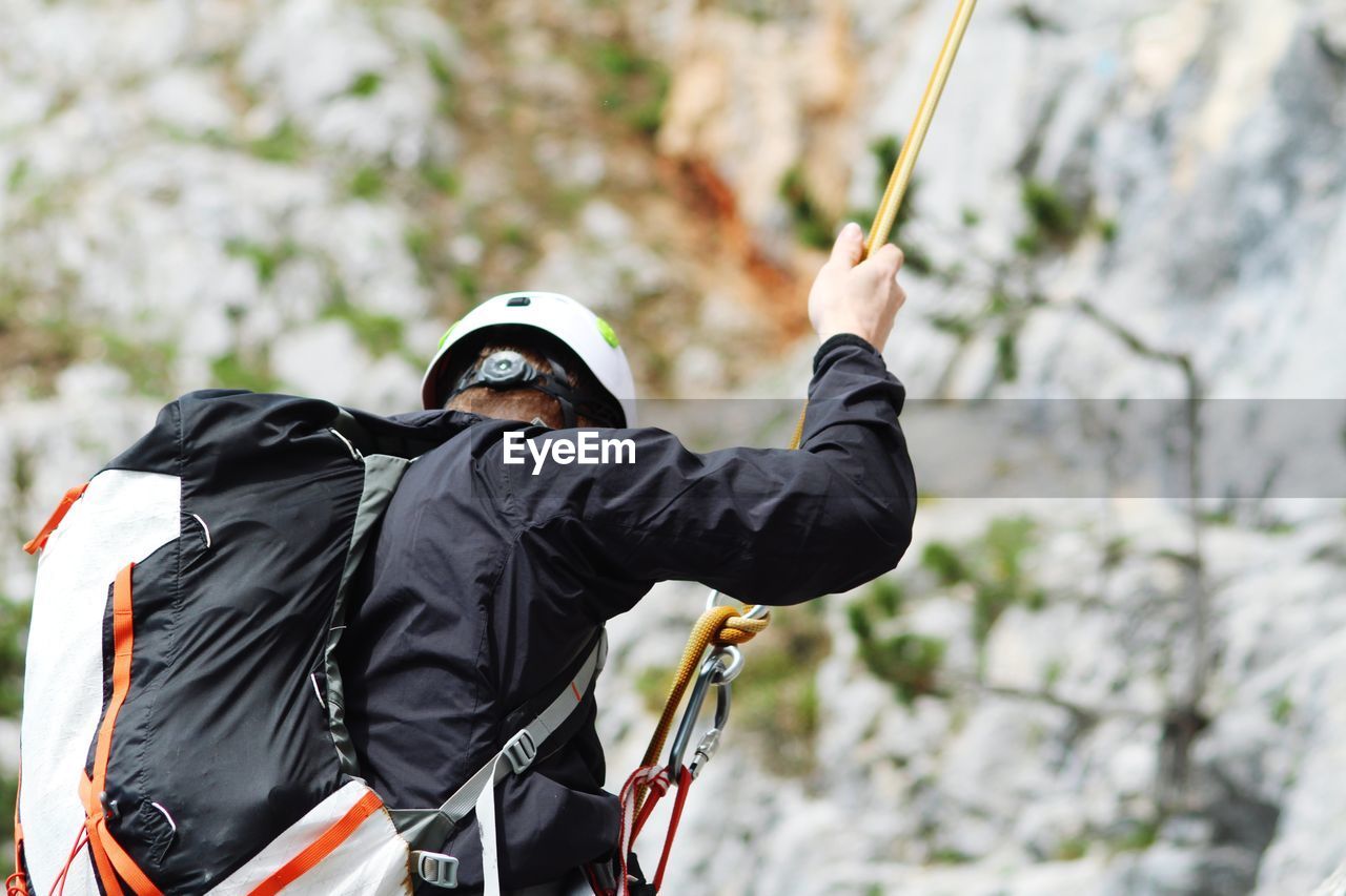 Man with backpack rappelling on mountain