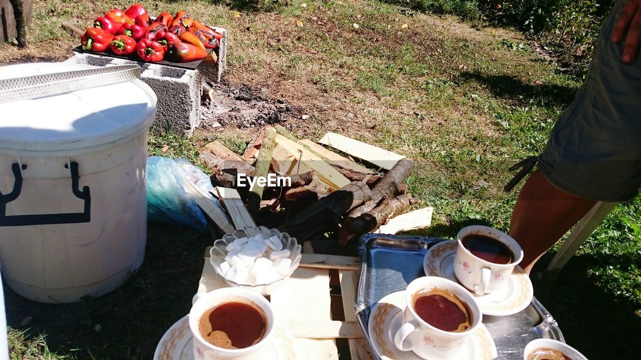 Low section of man standing by coffee cups at campsite