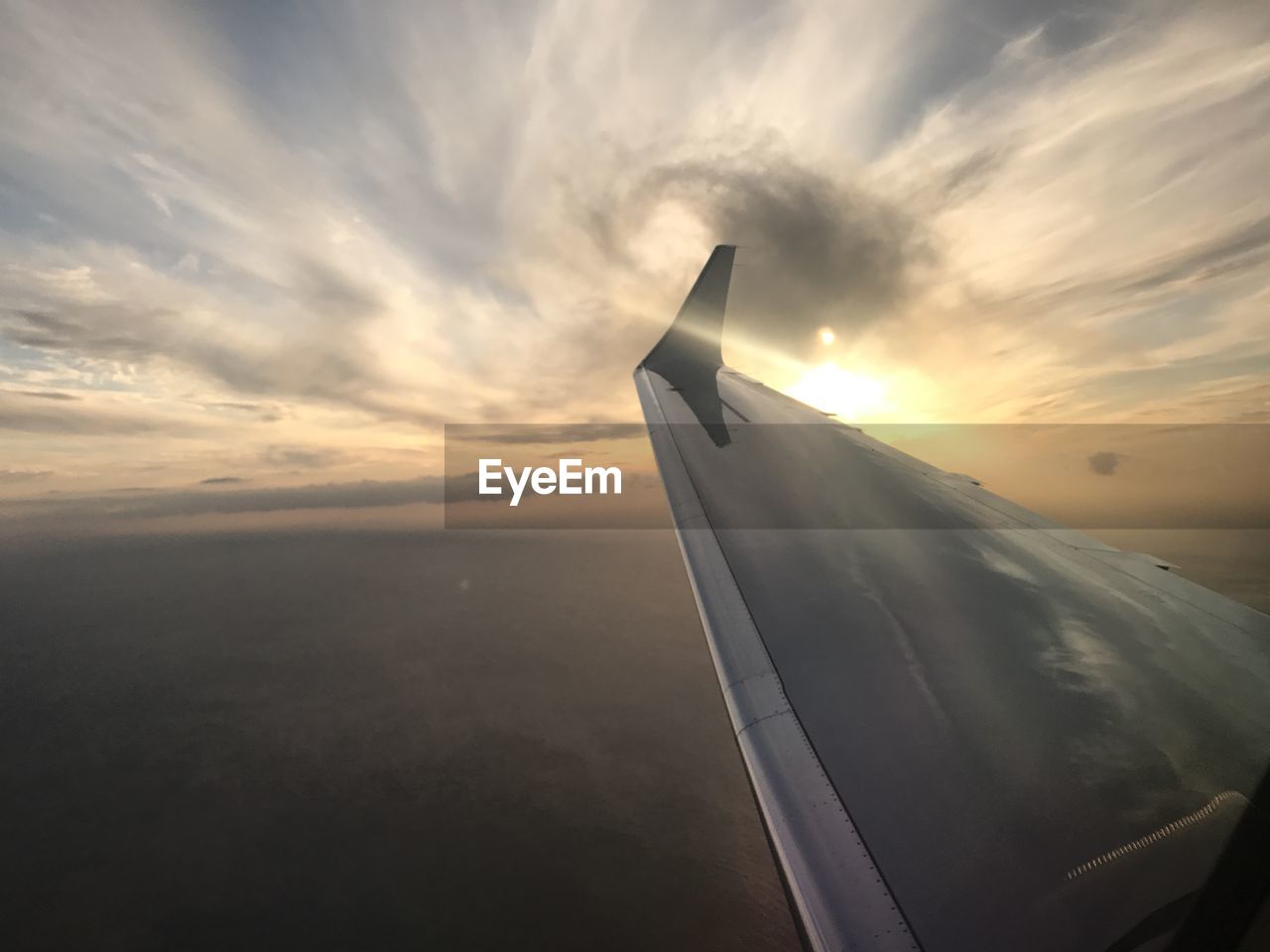 CLOSE-UP OF AIRCRAFT WING OVER SEA AGAINST SKY