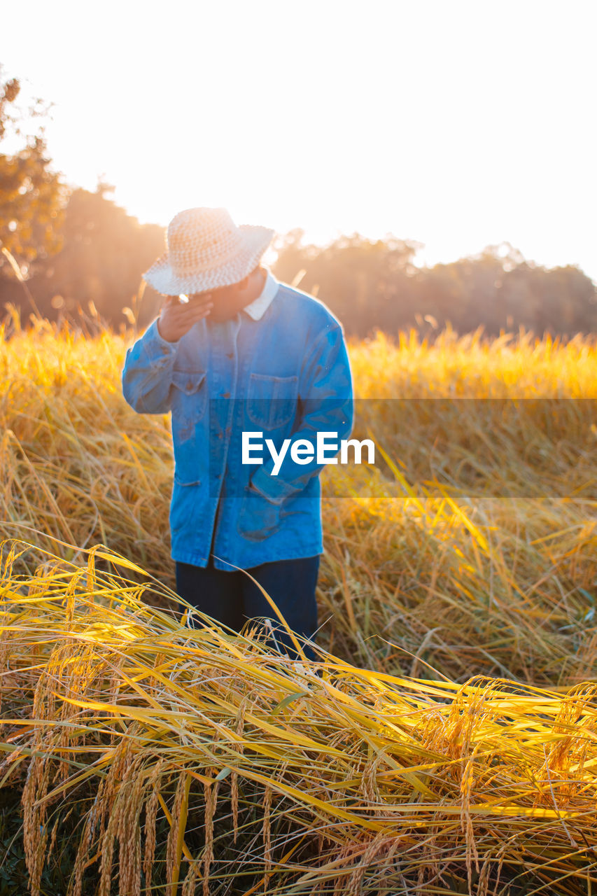 Man standing on field against sky during sunset