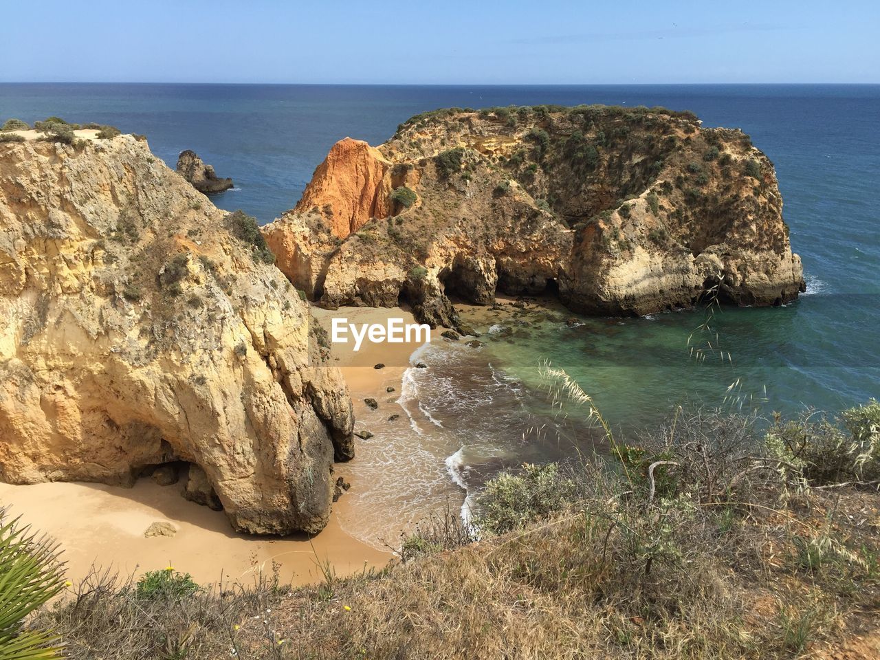 Rock formations by sea against clear sky