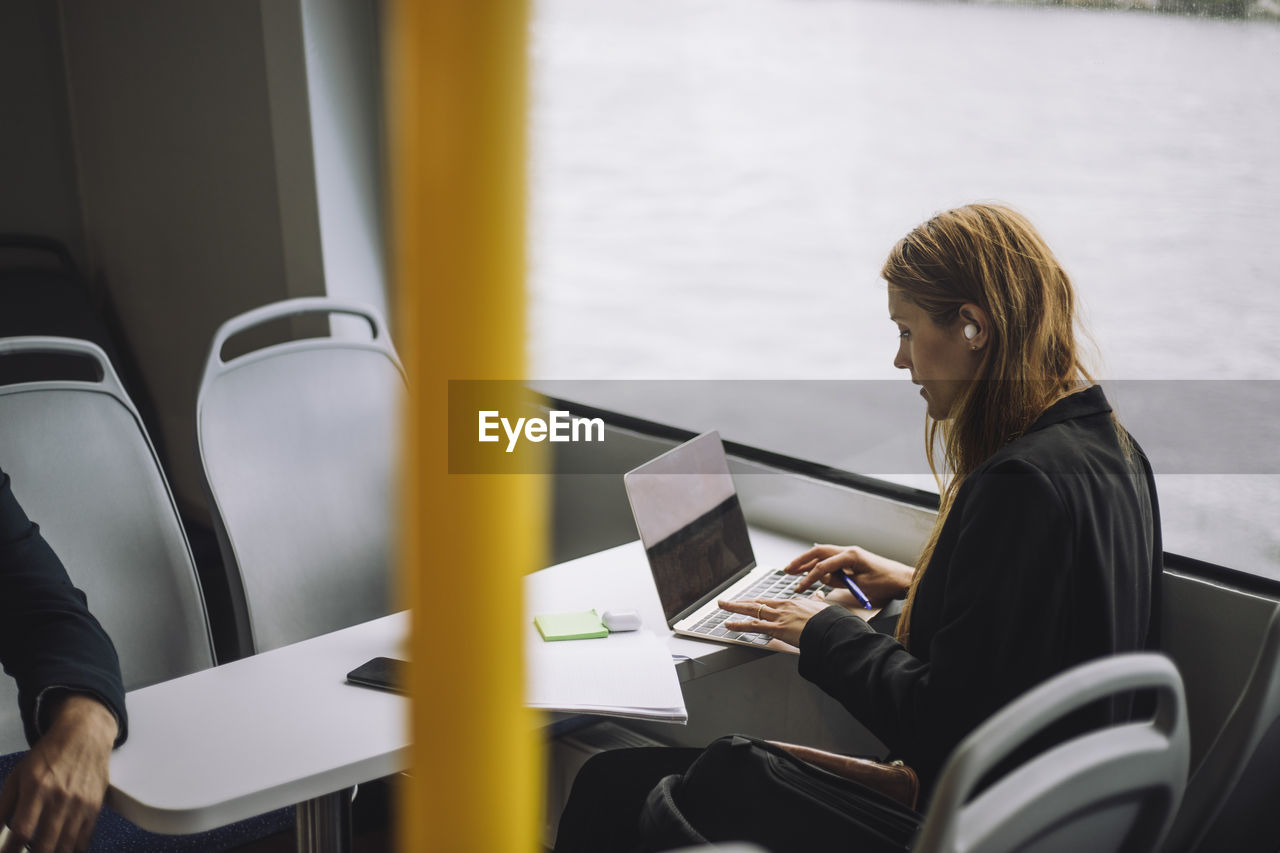 Female entrepreneur typing on laptop while sitting in ferry