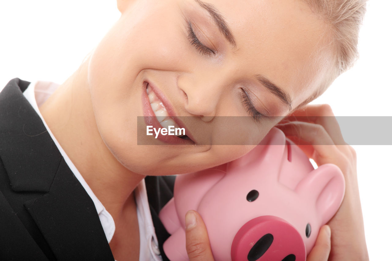Close-up of businesswoman with piggy bank against white background