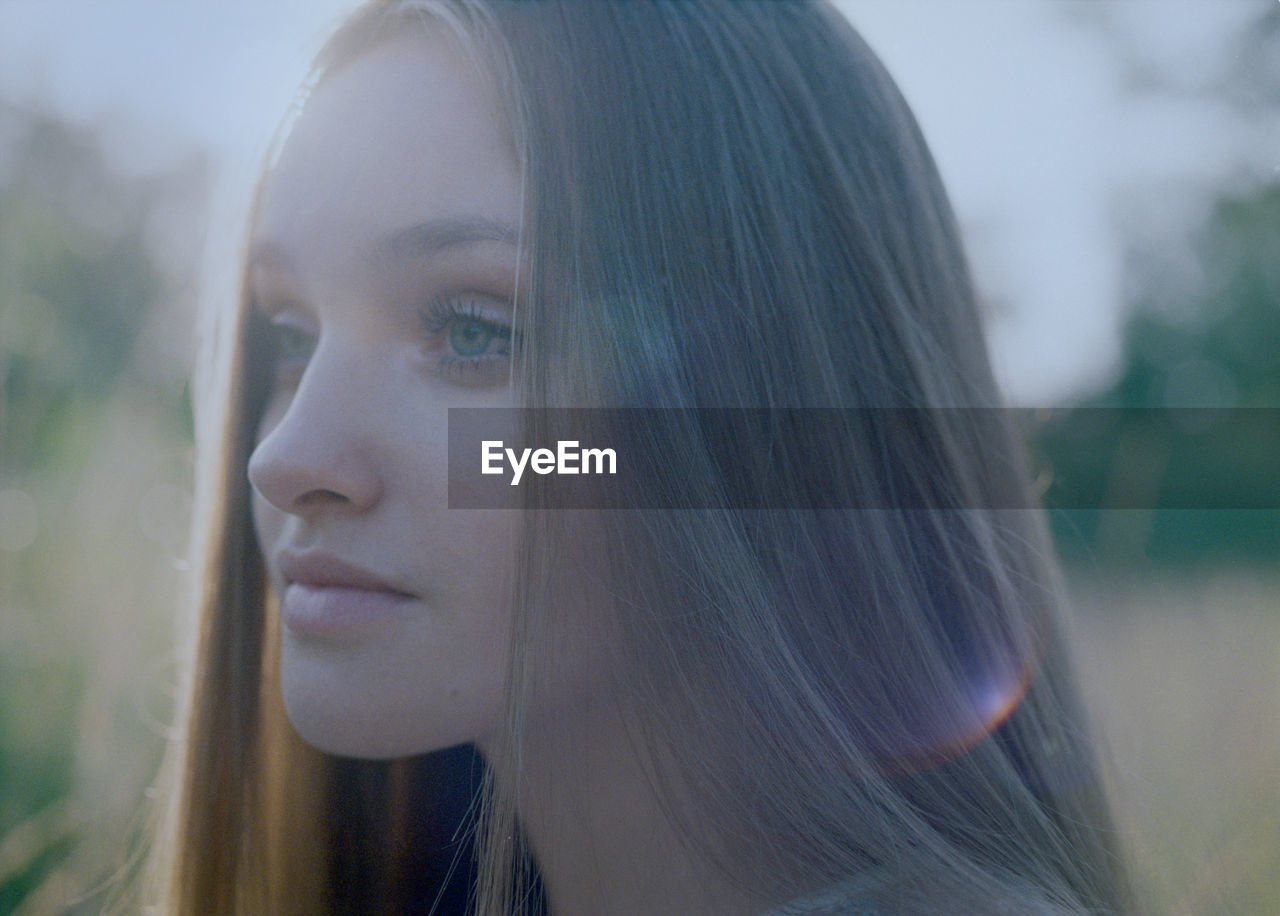 Close-up of the face of a young woman at dusk in the forest.