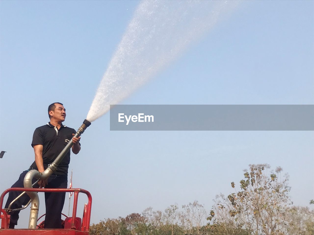 Man holding hose against sky