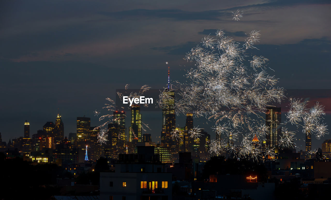 Firework display and illuminated buildings in city at night