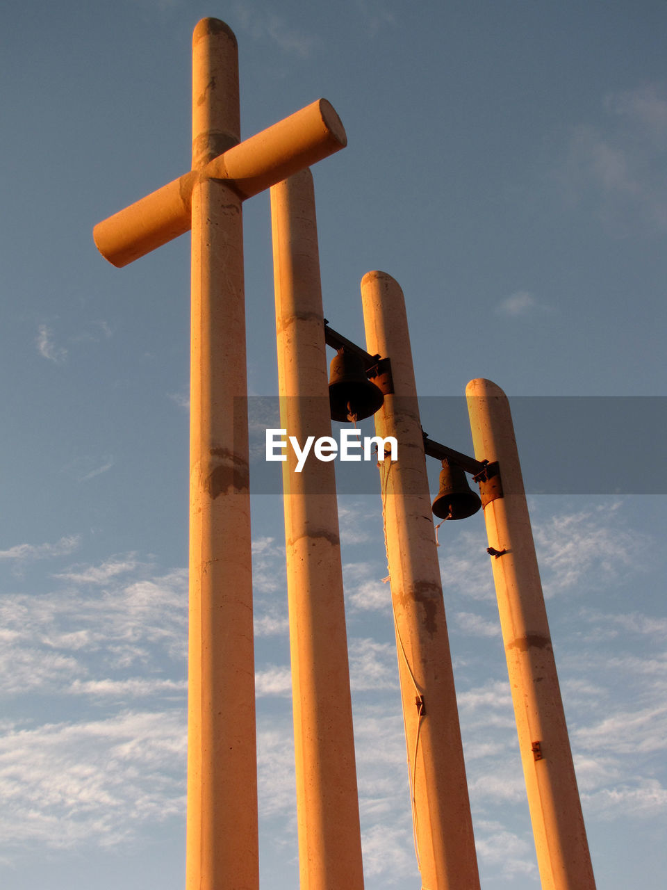 Low angle view of wooden cross by bells at ermita de sant roc against sky