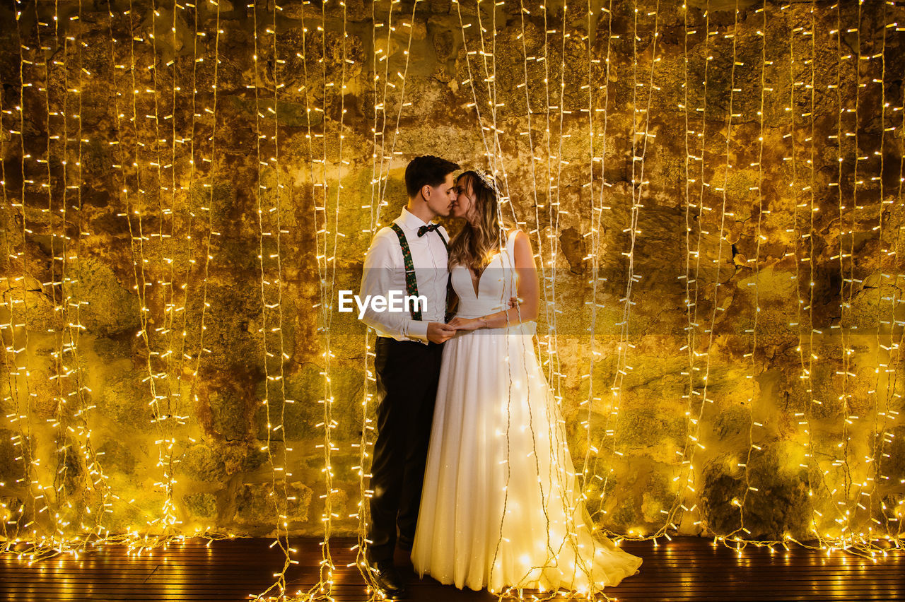 Full length of couple embracing against illuminated lighting