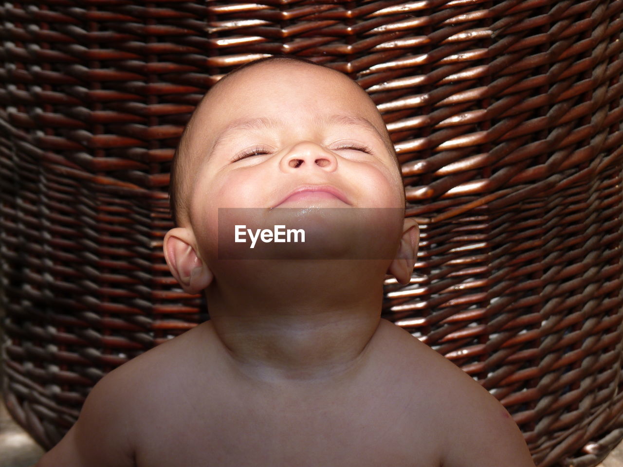 Close-up of baby boy sitting in front of basket