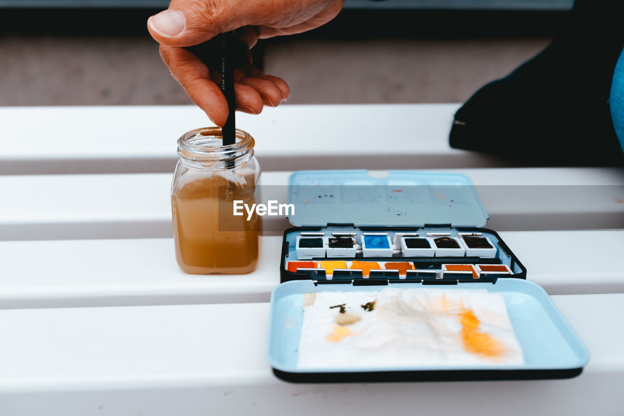 Cropped image of person with painting equipment on table