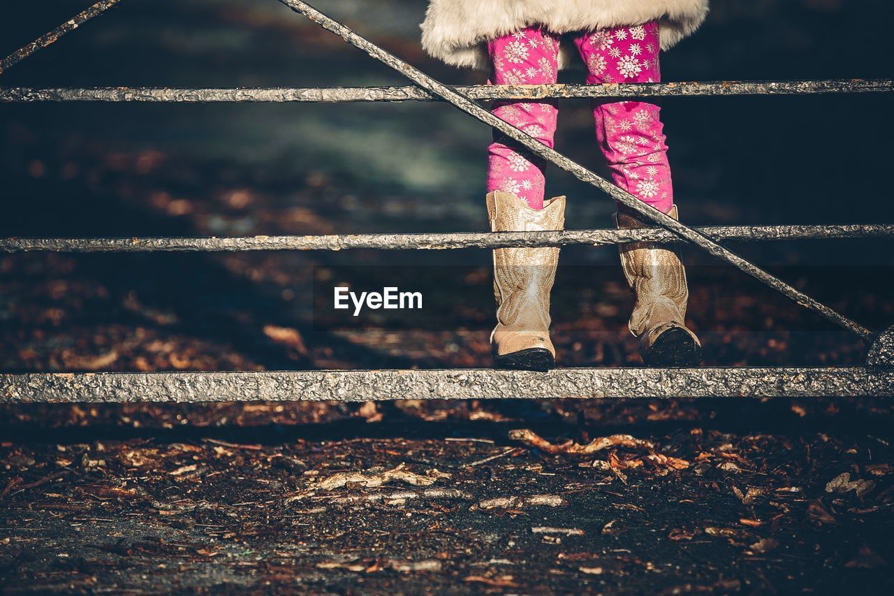 Low section of girl standing on gate