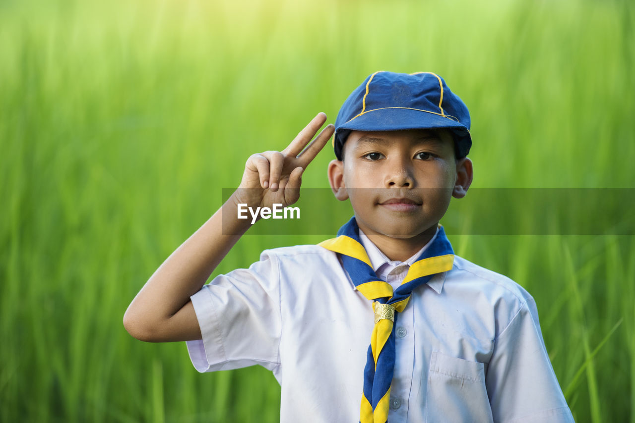 Portrait of boy standing wearing cap gesturing while standing outdoors