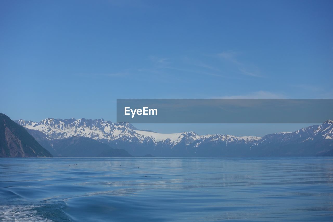 Scenic view of snowcapped mountains by sea against sky