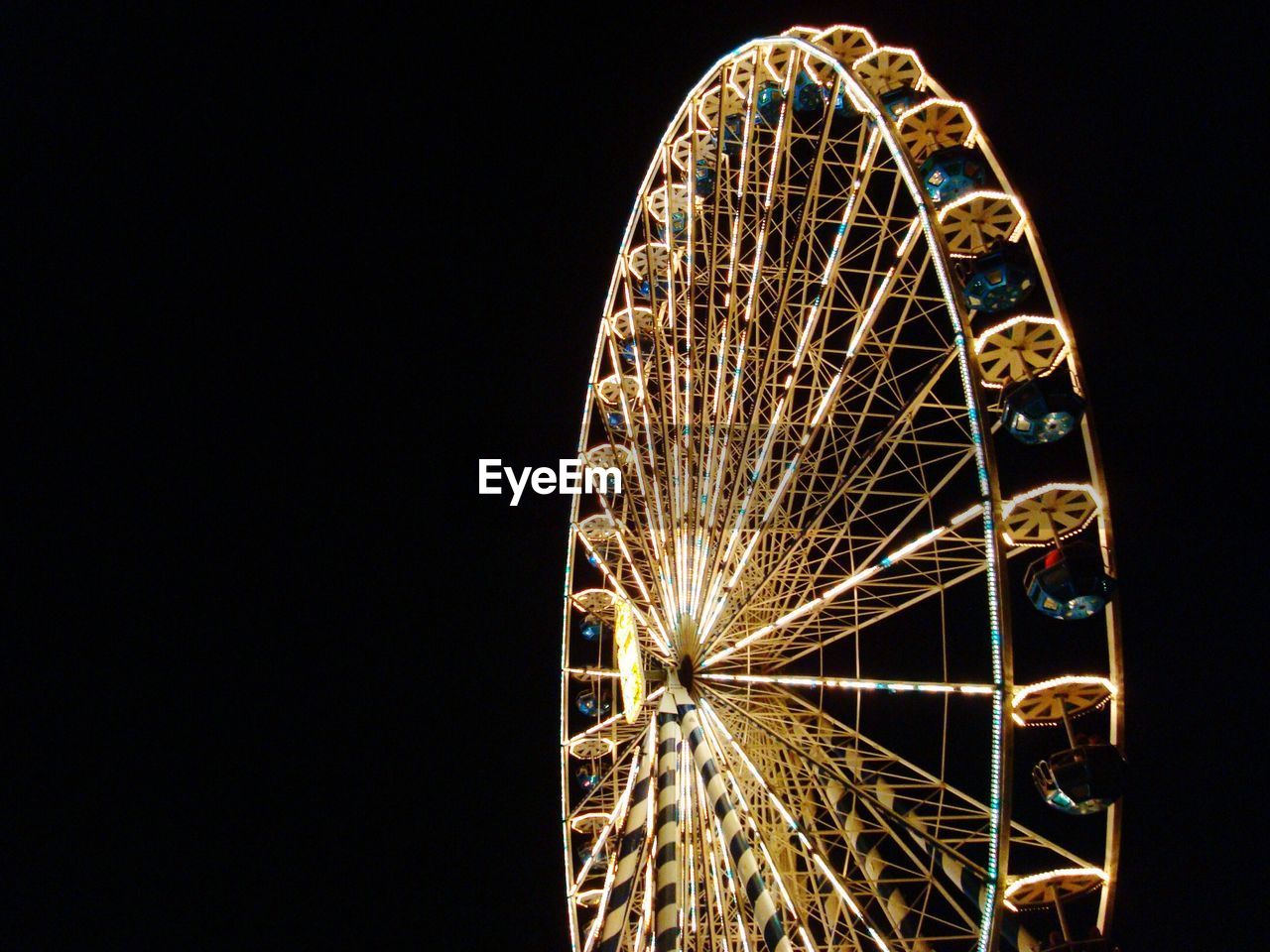 Low angle view of illuminated ferris wheel against clear sky