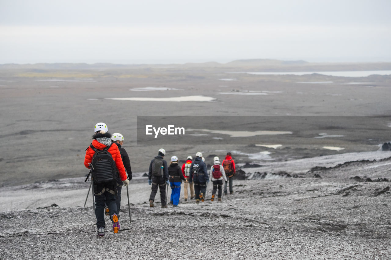 Rear view of people walking on landscape