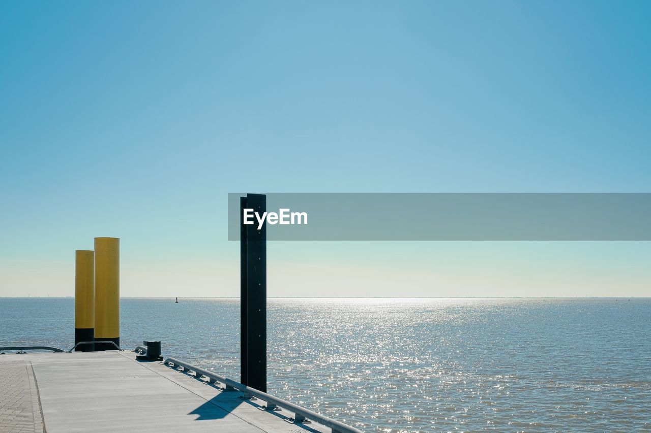 Scenic view of sea against clear blue sky with the edge of a pier
