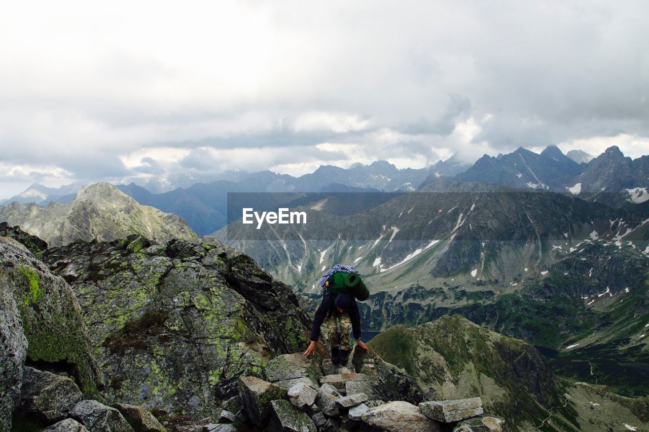 Person bending on mountain against sky