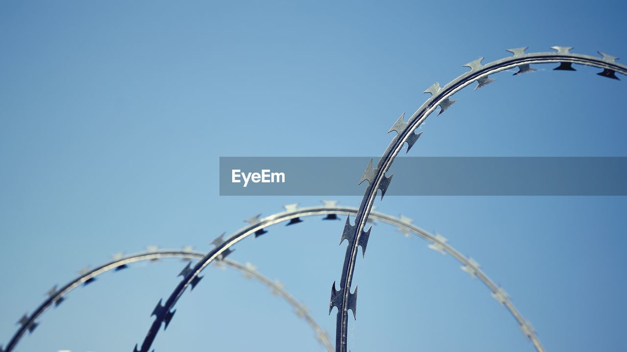 Low angle view of razor wire against clear sky