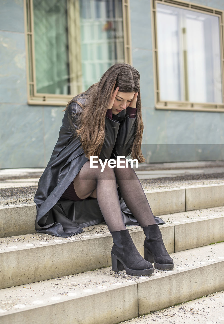 side view of young woman sitting on staircase