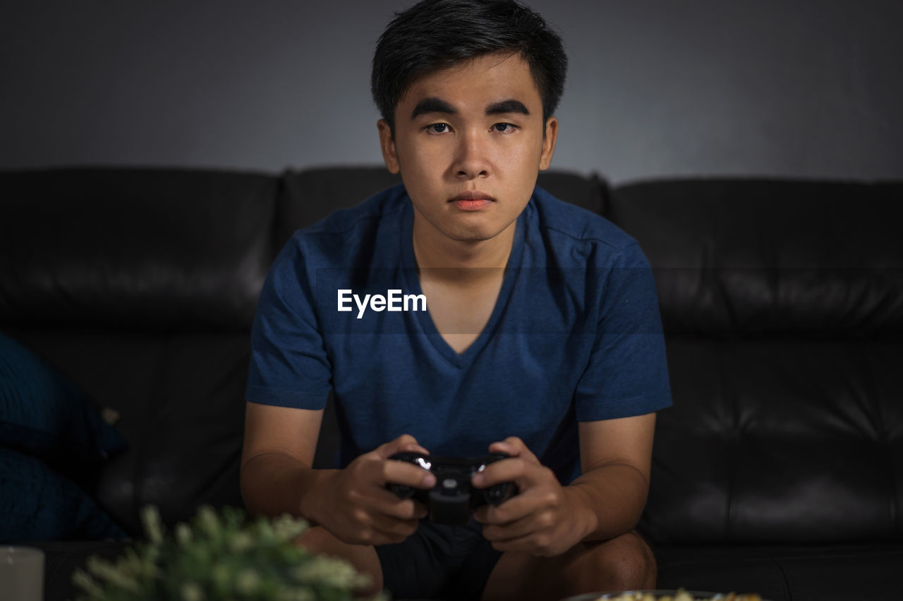 YOUNG MAN USING MOBILE PHONE AT HOME