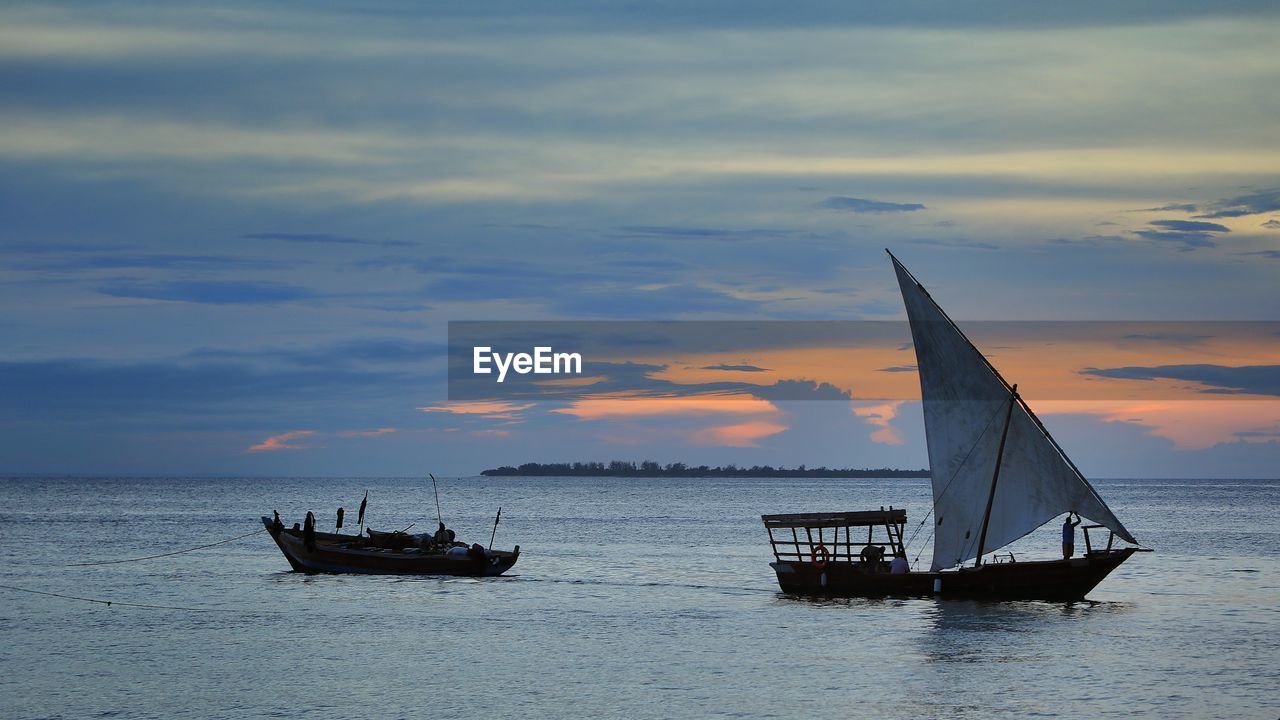 Sailboat sailing on sea against sky during sunset