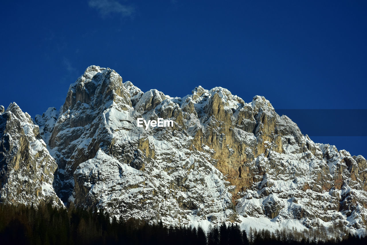 snow, mountain, cold temperature, winter, sky, scenics - nature, nature, beauty in nature, mountain range, environment, landscape, snowcapped mountain, blue, no people, plant, tranquility, mountain peak, clear sky, tree, tranquil scene, coniferous tree, pine tree, land, pinaceae, outdoors, rock, travel destinations, non-urban scene, extreme terrain, day, travel, frozen, forest, pine woodland, ice
