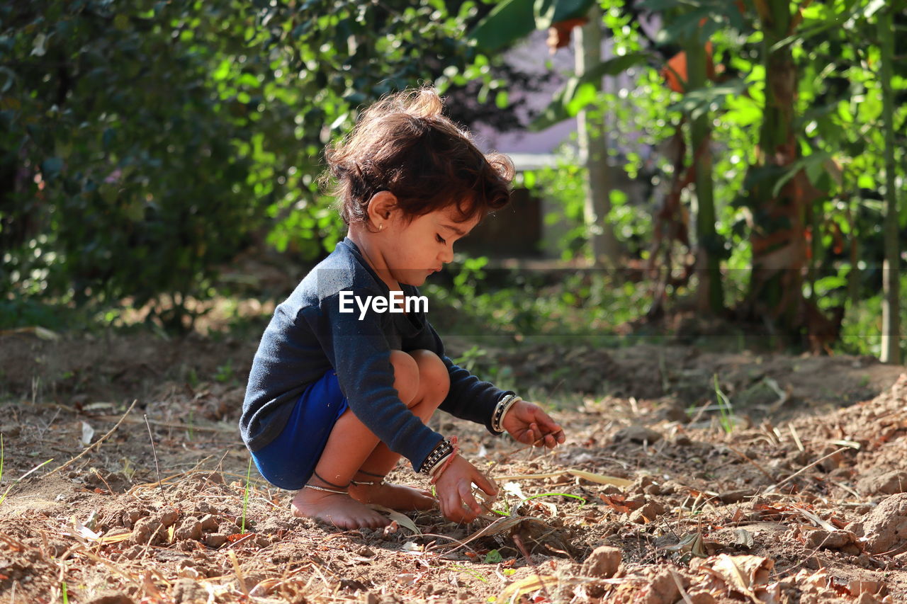 Side view of boy playing in the garden with sand