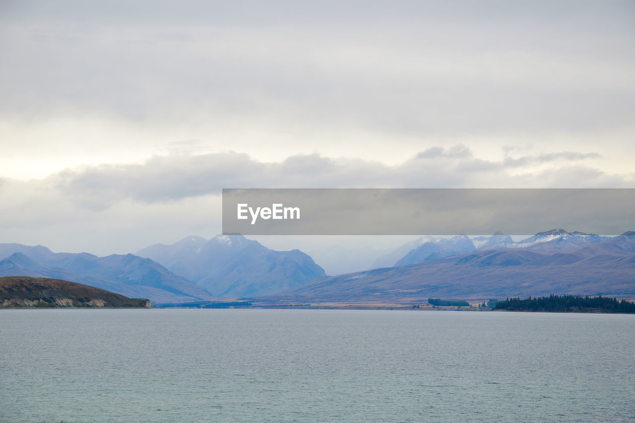 Scenic view of lake by mountains against sky