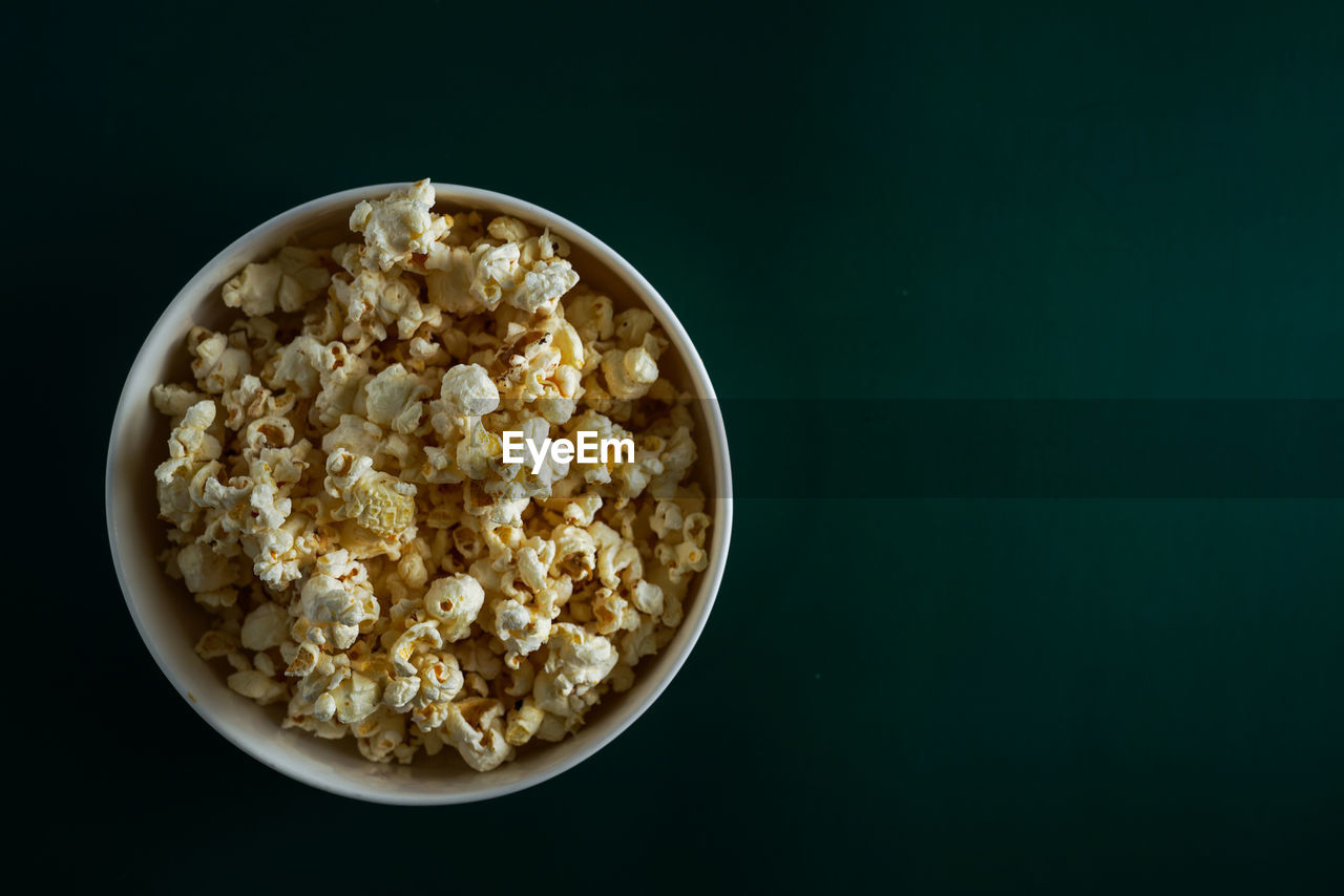 High angle view of popcorn in bowl against dark green background