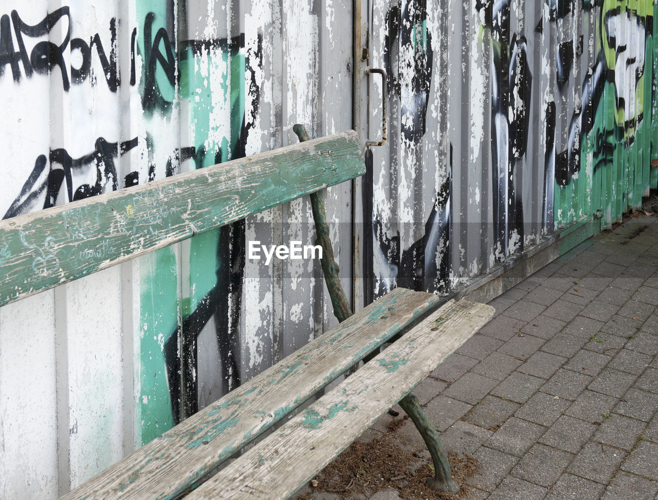 Empty old bench by graffiti wall