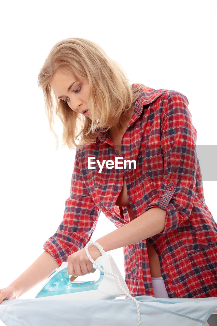 Woman ironing clothes against white background