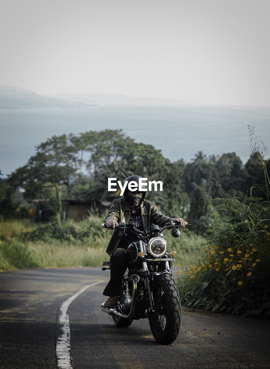 Rear view of man riding motorcycle on road