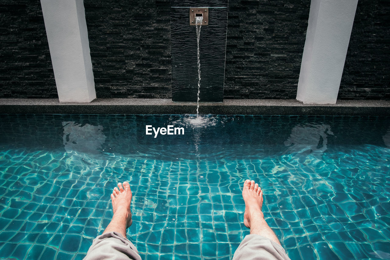 Low section of man relaxing in swimming pool